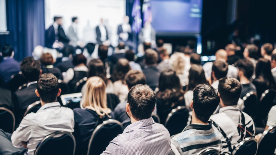 Large crowd at a business event panel discussion
